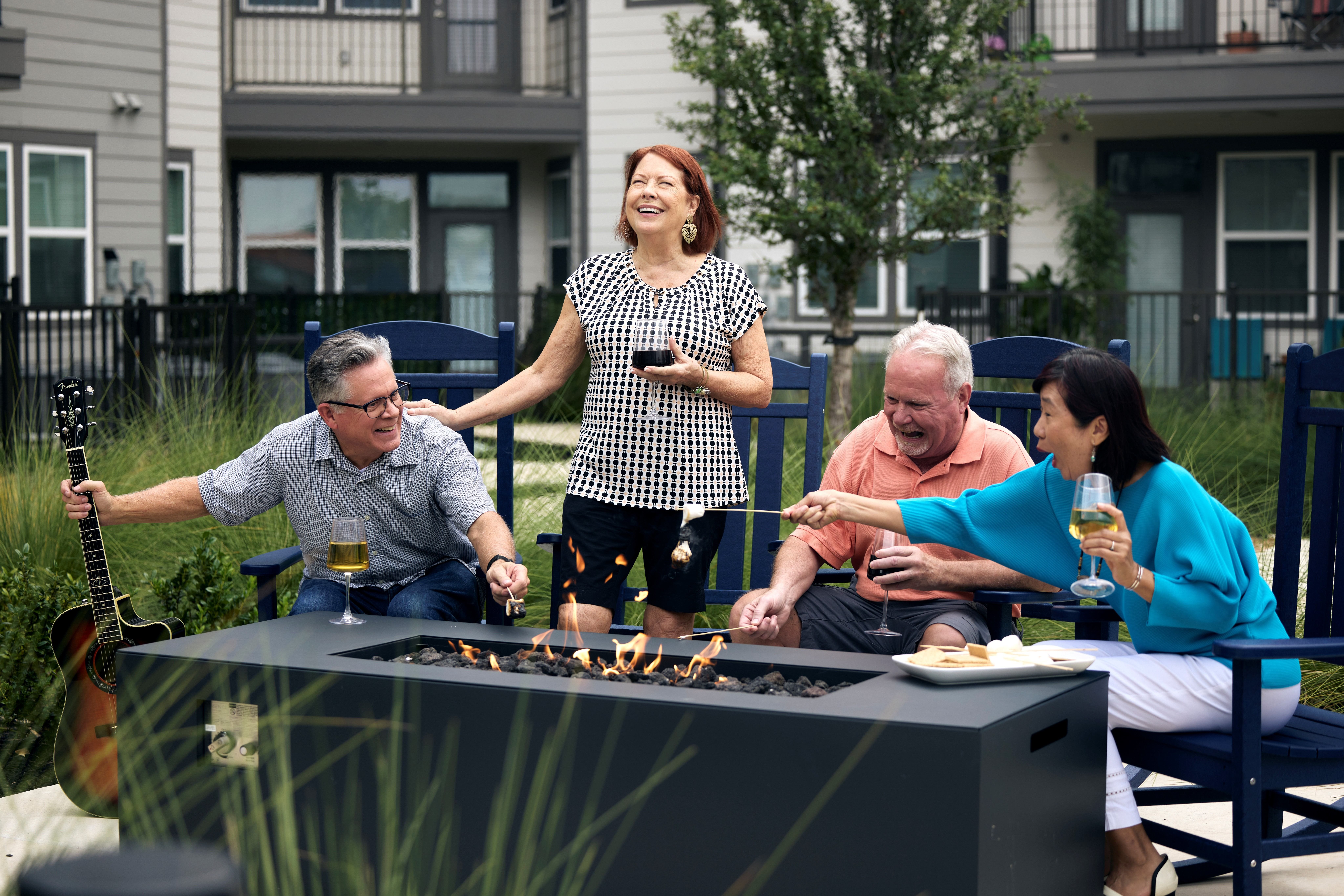 A group of people are gathered around a grill, enjoying a meal and drinks.
